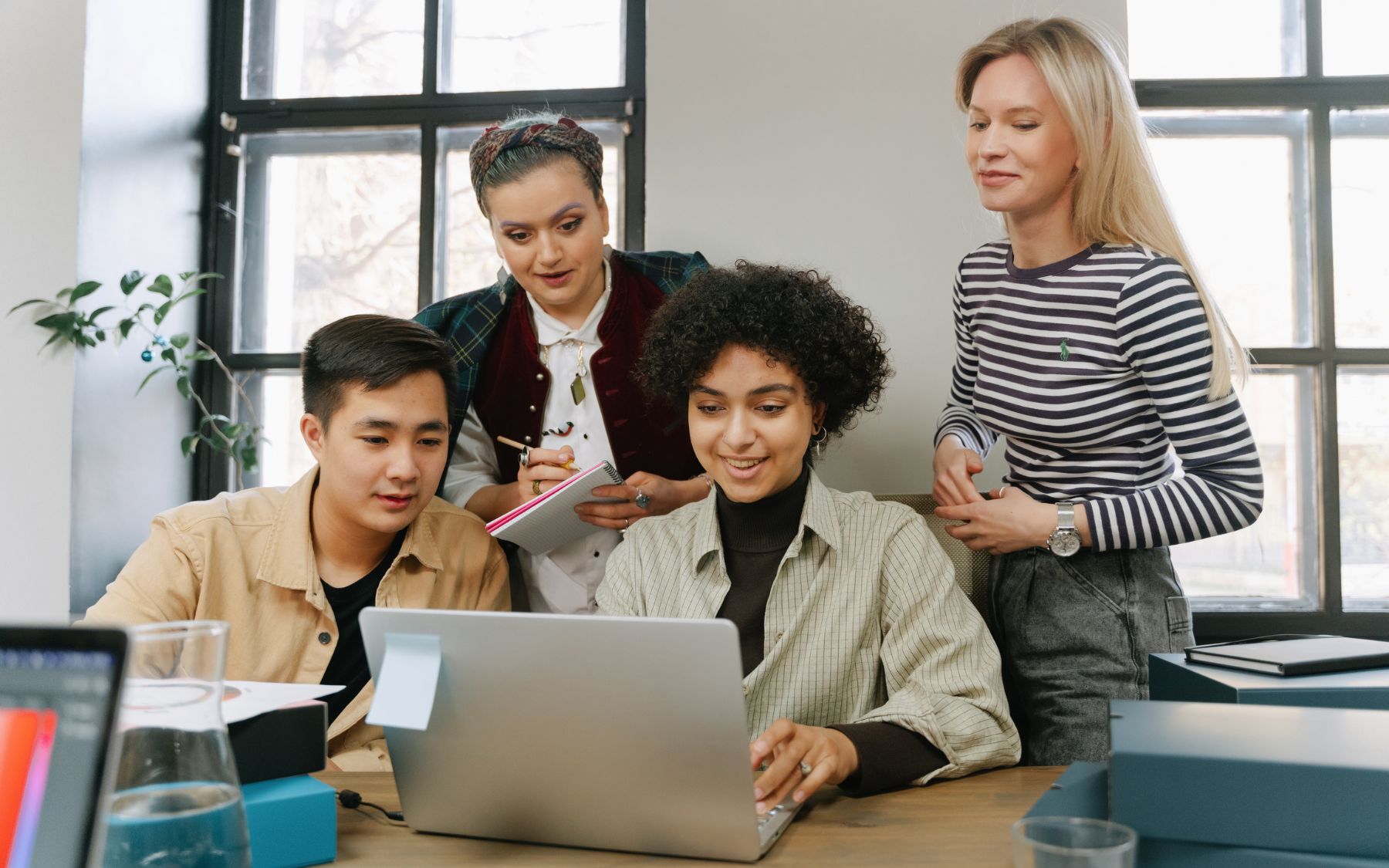 Four people reviewing project work together around a laptop